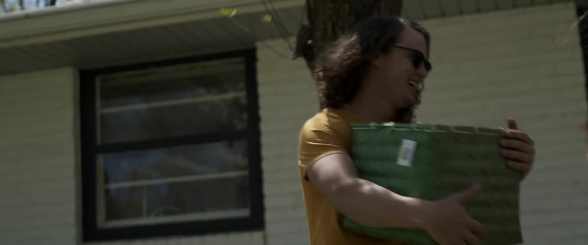 A man grabs a box from a woman to help her carry into a house