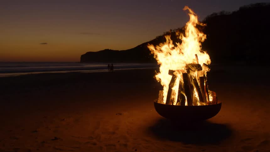 Bright flames from a bonfire on a beach after the sun has set