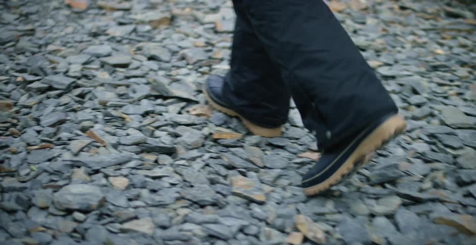 A person walking over rocks in boots and snow pants