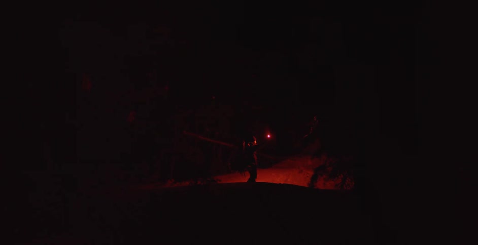 A hiker holding up a flare while standing in pitch black in nature