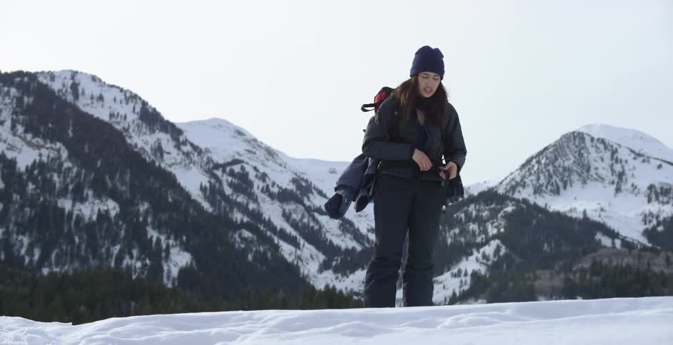 A woman catches her breath as he hikes to the top of a mountain