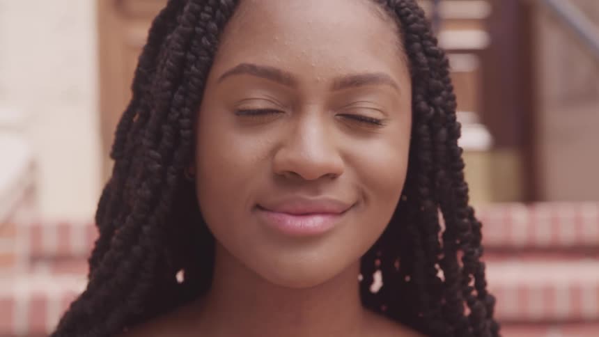 A young woman smiling and blinking while sitting on outdoor steps