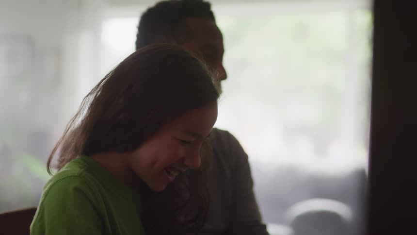 Father and daughter playing piano and singing in a room at home