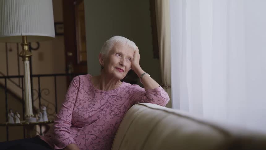 A woman is sitting on the couch looking out the window