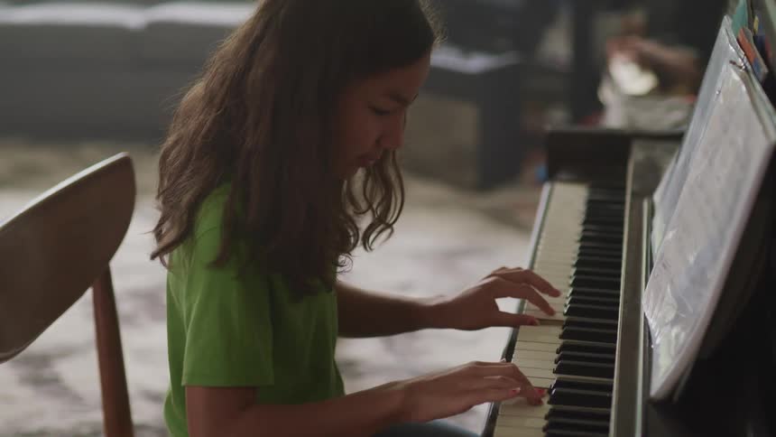 Young girl playing piano in a room at home