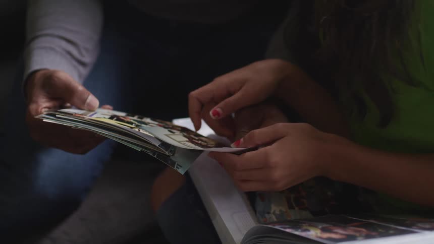 A man and a girl sitting and watching pictures as the girl laughs