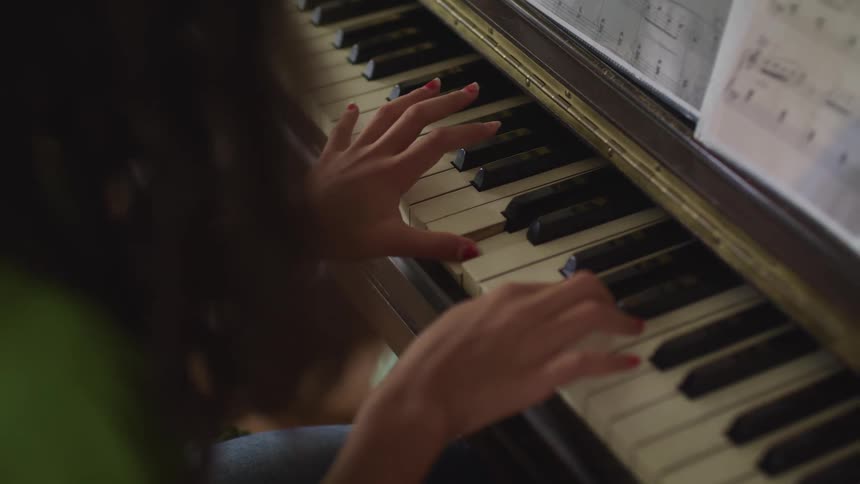 A girl sitting in a room playing a piano