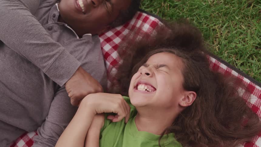 A man and a girl laying on a blanket on the grass