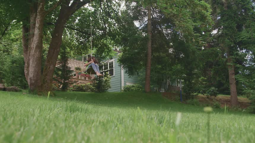 Girl swings on tree swing near house