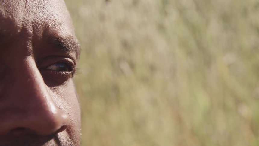 Close up of the eye of a man sitting on a field of grass
