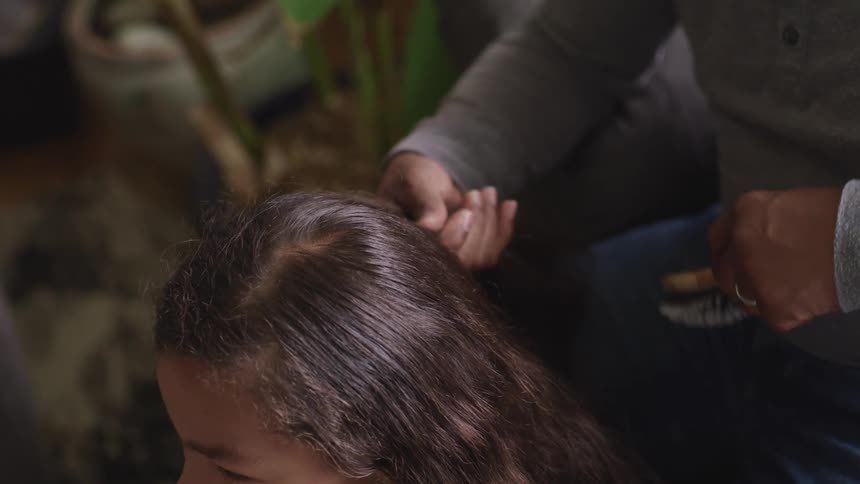 A person that is brushing an asian womans hair