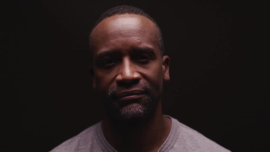 A man looking up and staring in front of a black background