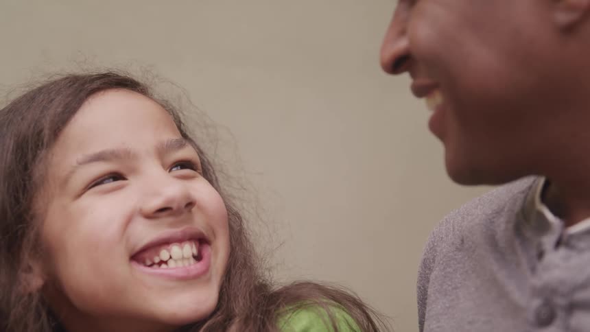 A man and a girl in a room smiling with a wall in the background