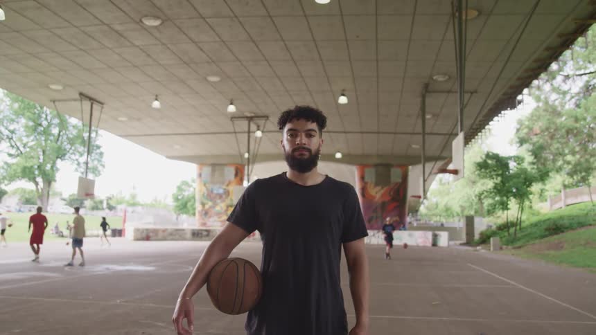 Young man holding a basketball looking at the camera