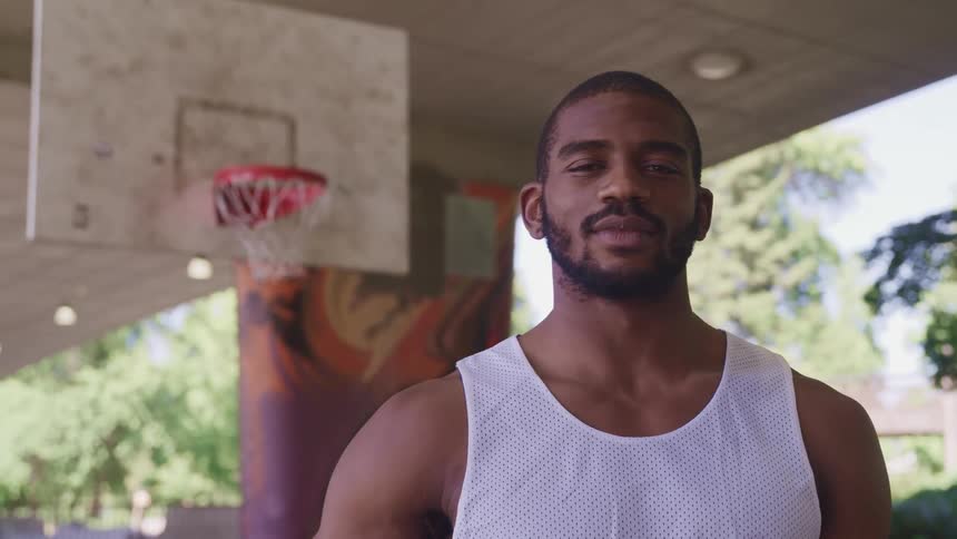Young man standing in a basketball court looking at the camera