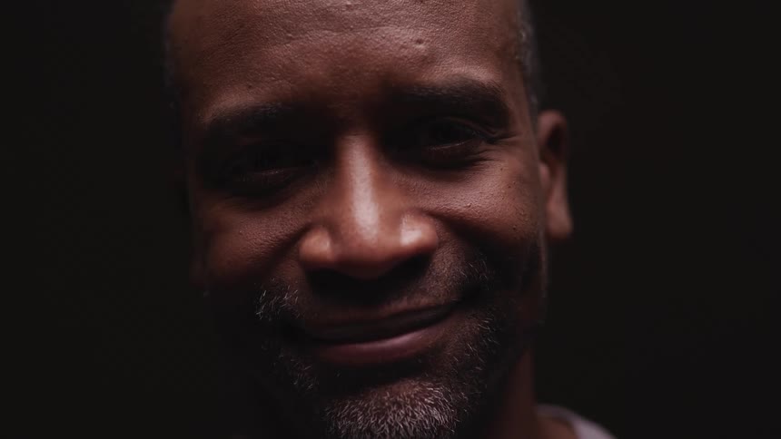 A man is smiling in the dark room
