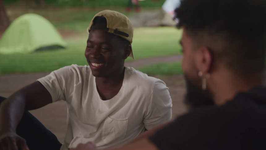 Two friends sitting on the ground in a park shake hands