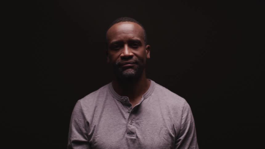 Man standing in a dark room looks up at the camera