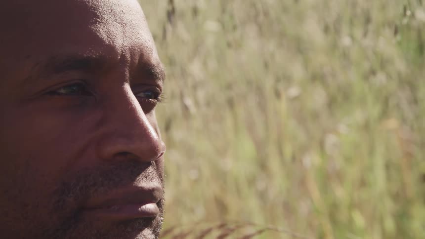 Close up of mans face looking around in a field