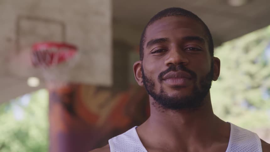 Young man standing on a basketball court looking at the camera