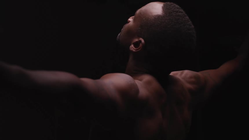 A man stretching in a room with a black background