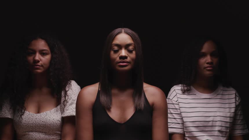Three woman in a room with a black background
