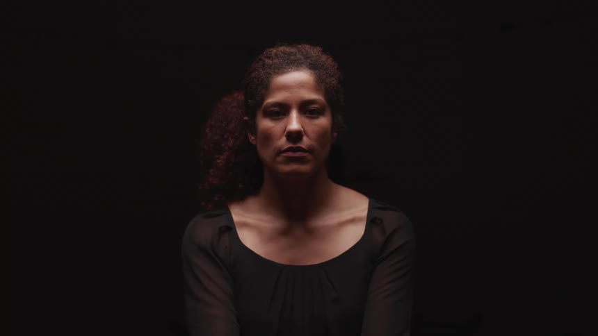 A portrait of a woman sitting in a dark room