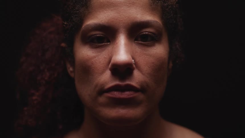 A woman with a nose ring in a room with a dark background