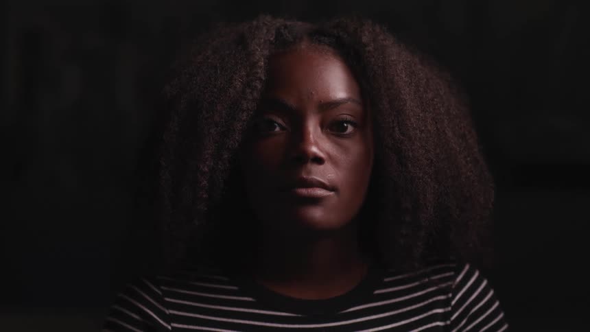 A young woman slowly lifts her head to look at the camera while posing for a portrait