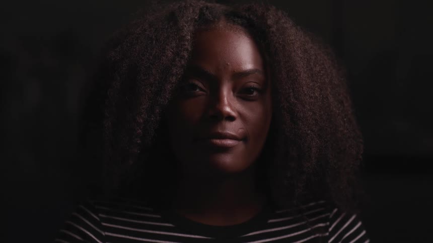 A woman in a room with a wall in the background