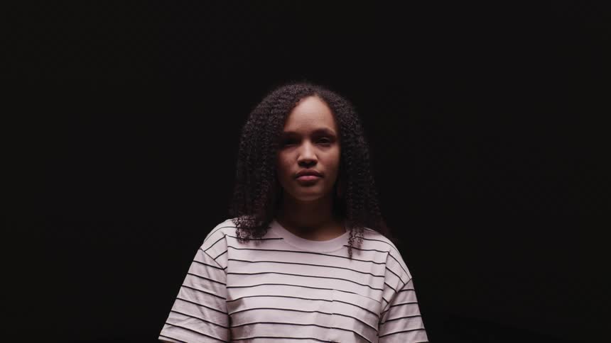 Woman standing in a dark room looks up to the camera