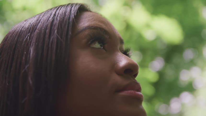 Close up of a womans face looking up in the forest