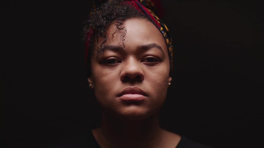 Young woman wearing a red headwrap in a dark room