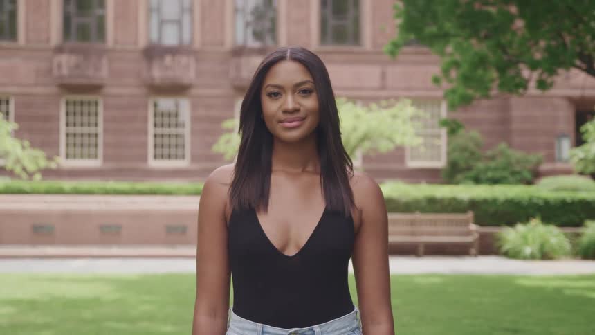 A woman is standing on the lawn in front of the building