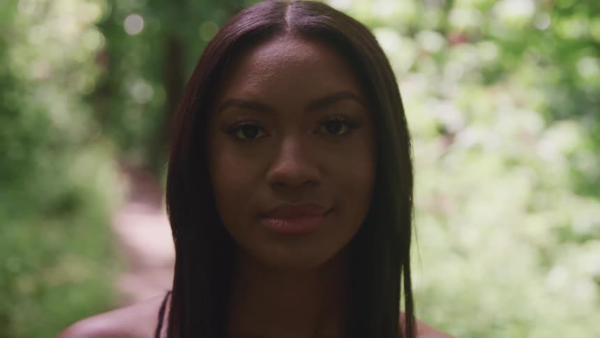 Young woman standing in a forest looking at the camera