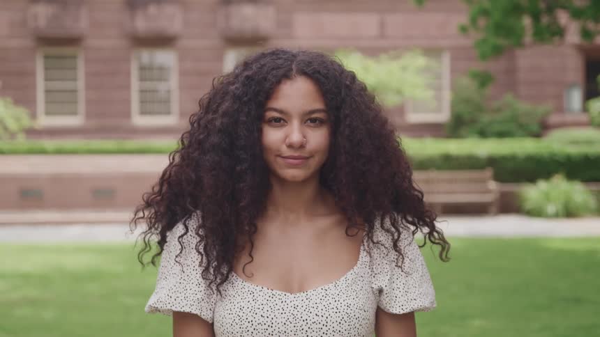 A young woman smiling for a portrait outside on a summer day