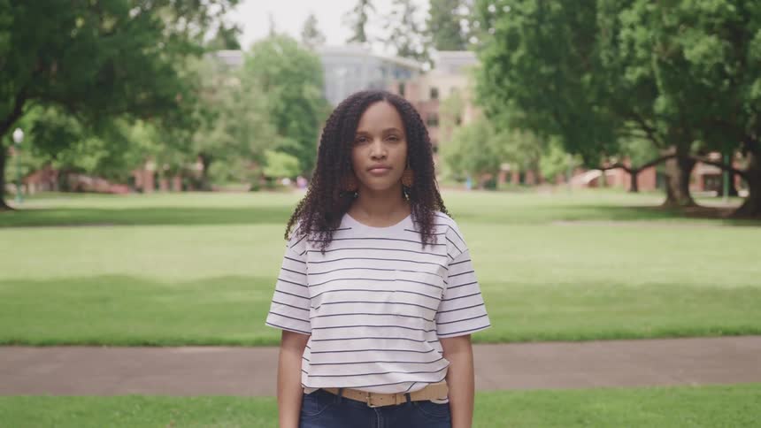 A woman in a striped shirt standing outside on a grassy lawn