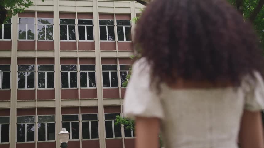 Woman with long curly hair looking at a building at daytime