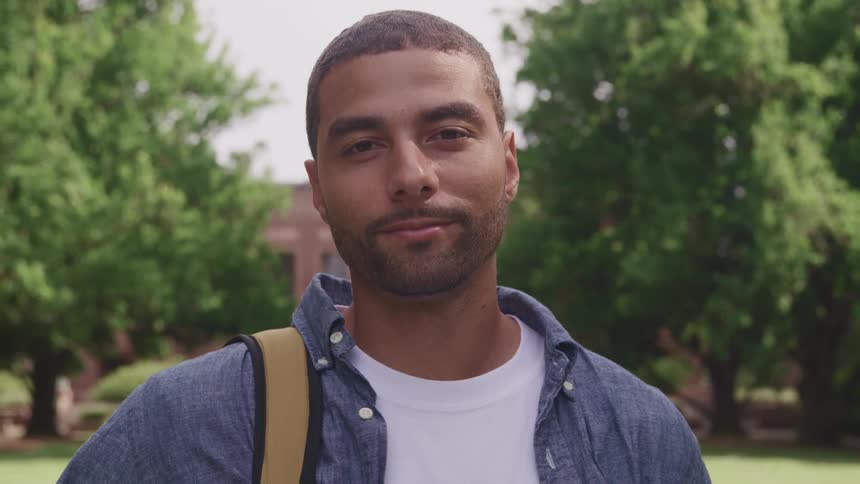 Young man standing on an university campus looking at the camera