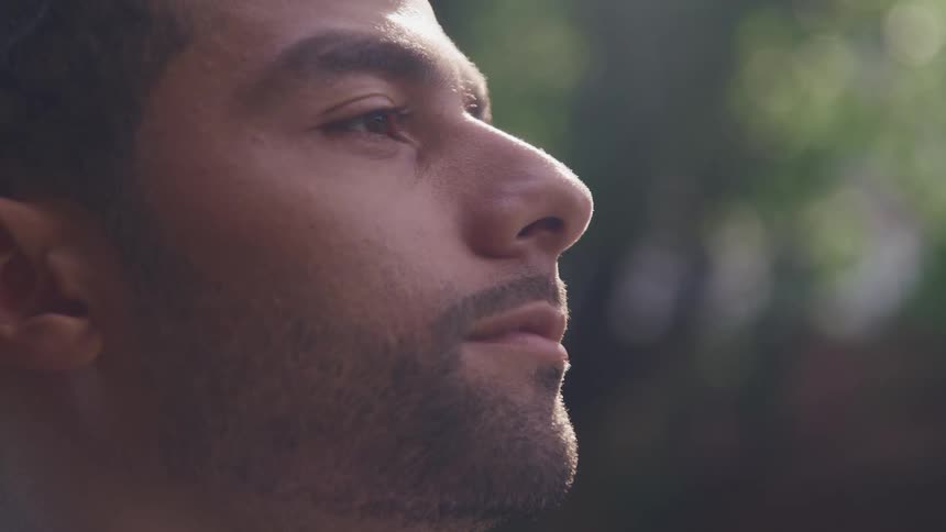 Close up of a man closing his eyes outside and then looking straight ahead