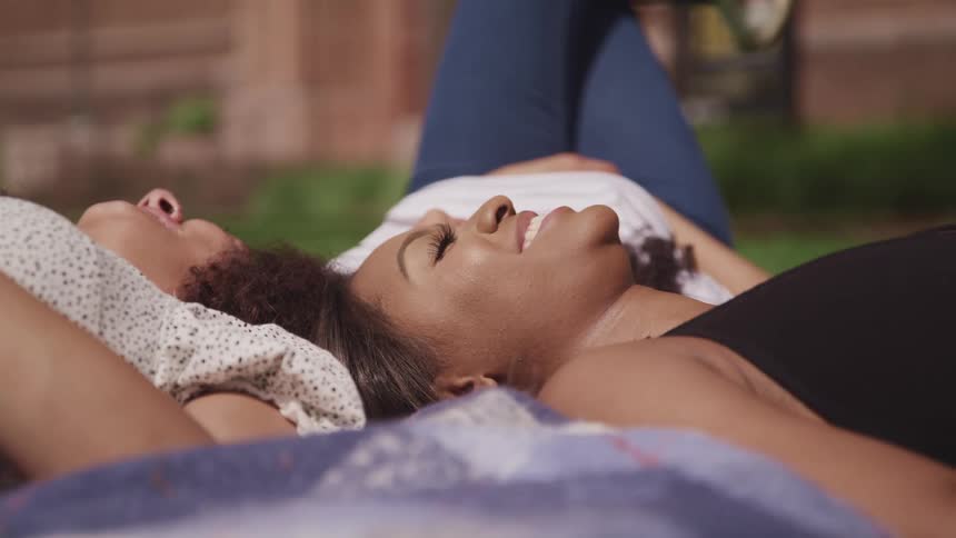 Three female friends lying on the ground together on a summer day