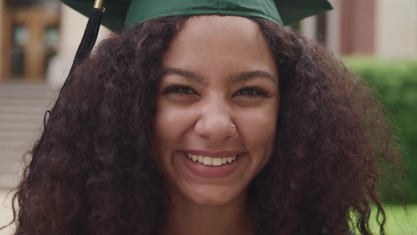 A female graduate smiling outside while wearing a graduation cap