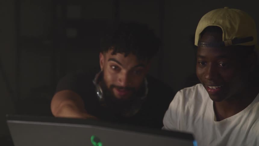 Two teenage boys look at a computer and laugh and talk