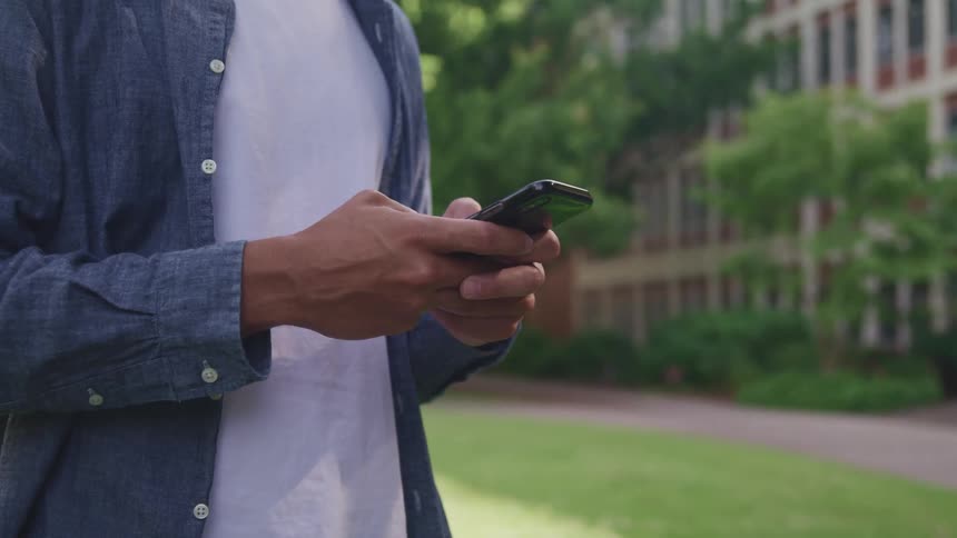Man texting on a smartphone in the campus of a university