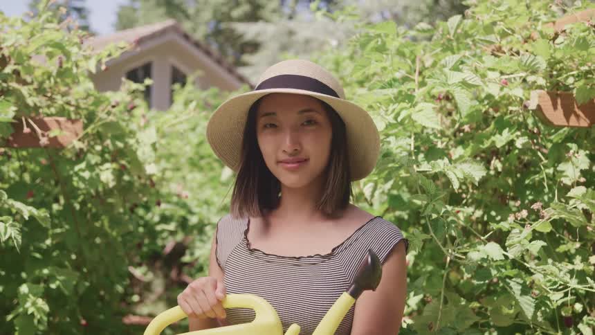 A woman is watering her garden outside
