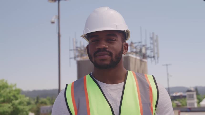 A portrait of a man in a vest and hardhat