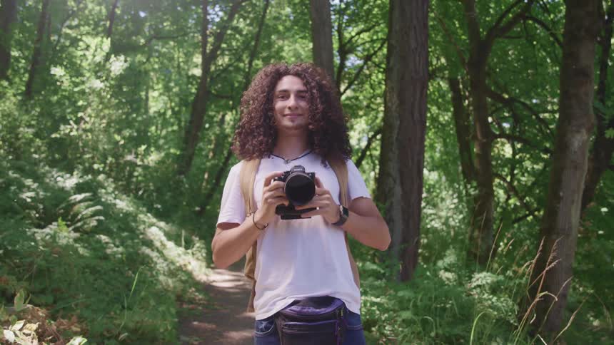 Young man with slr camera on trail in forest area