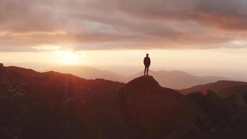 A man standing in the mountains on a rock cliff