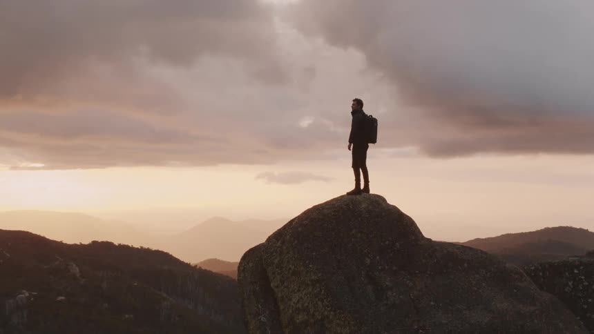 Man standing at the top of a rock at a cliff