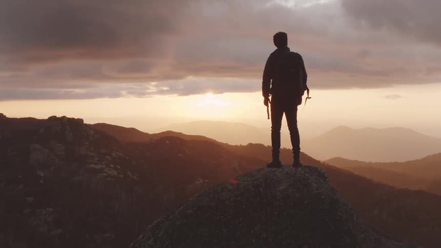 A man standing on a boulder on a mountaintop